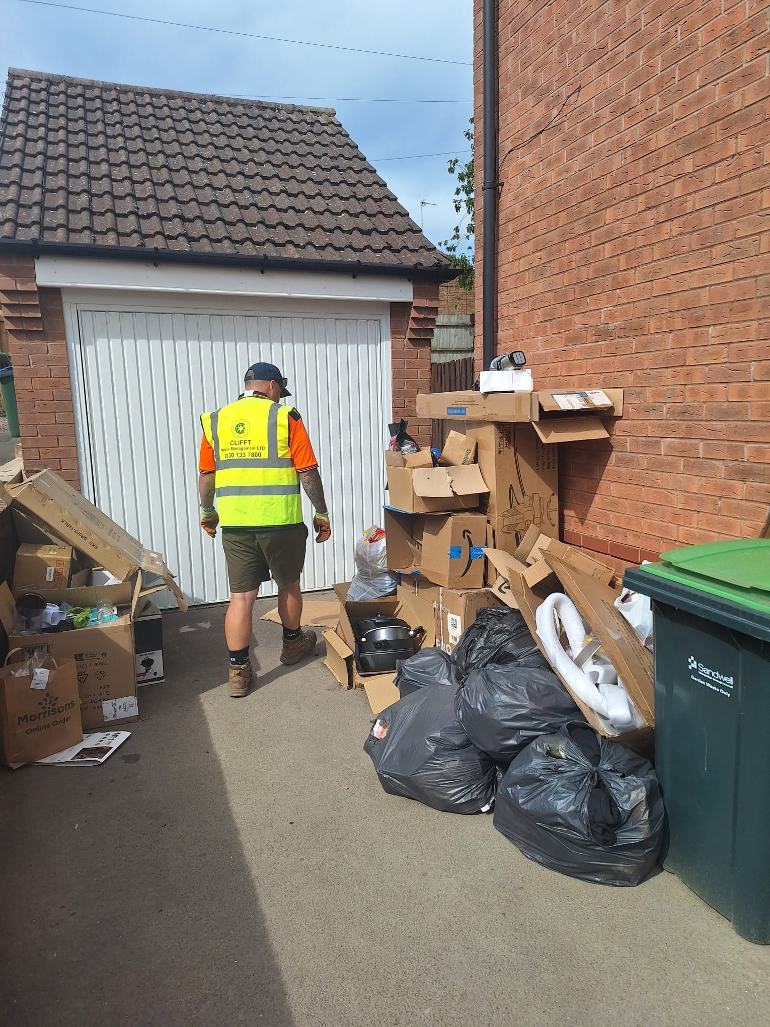 Waste collector beside cardboard awaiting clearance